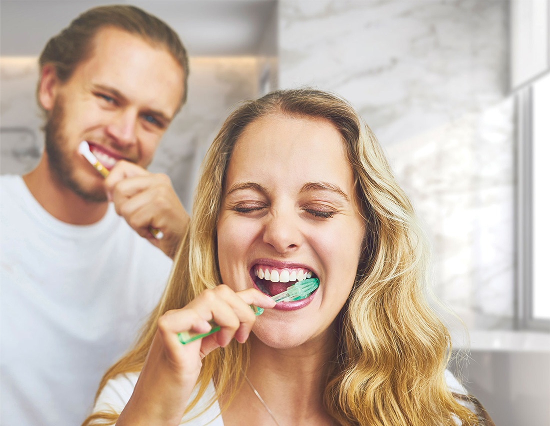 Mies ja nainen harjaavat hampaitaan